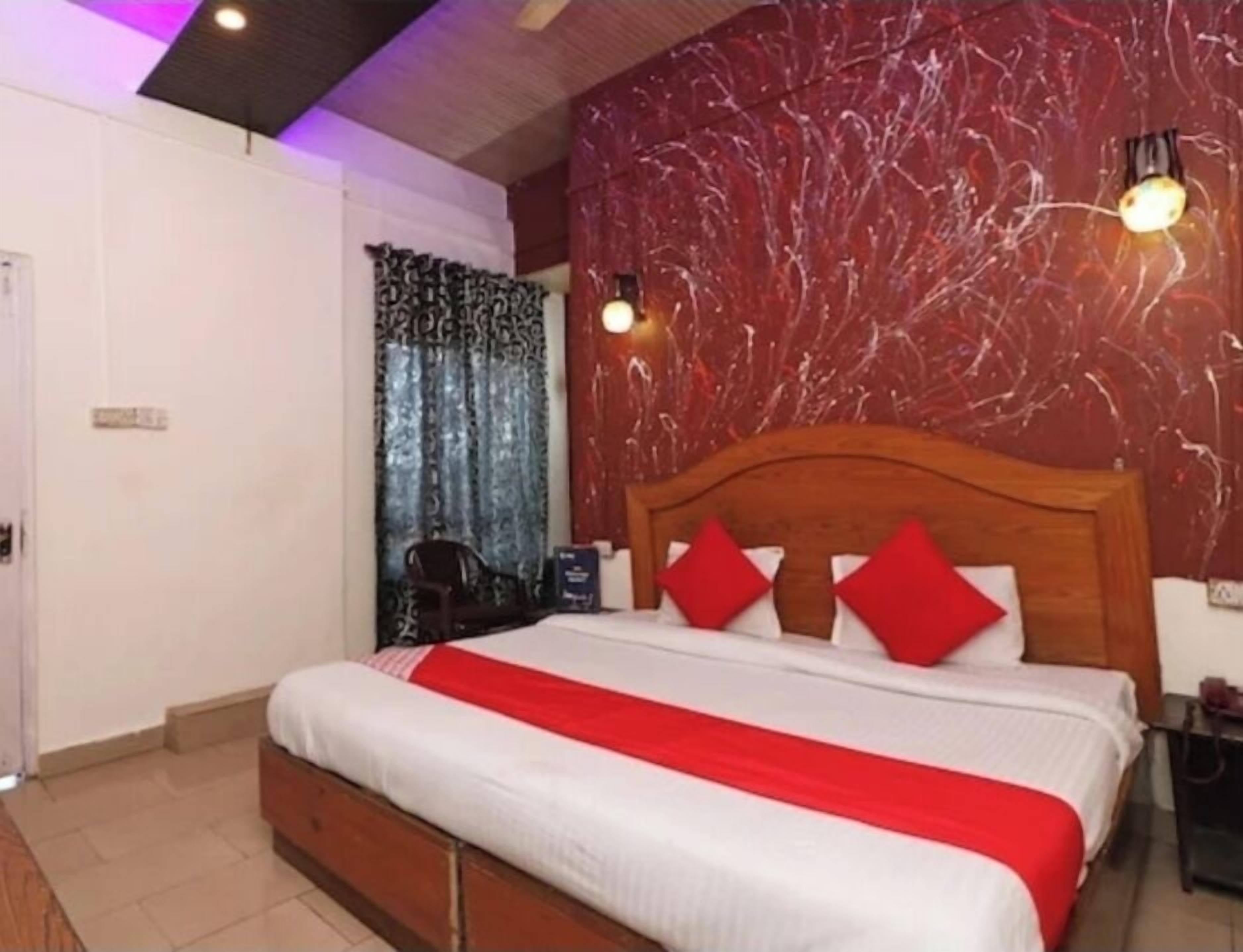 A bedroom with a large bed, a wooden headboard, and a red and white bedspread.