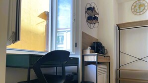 Una stanza compatta con scrivania, sedia e angolo cottura.