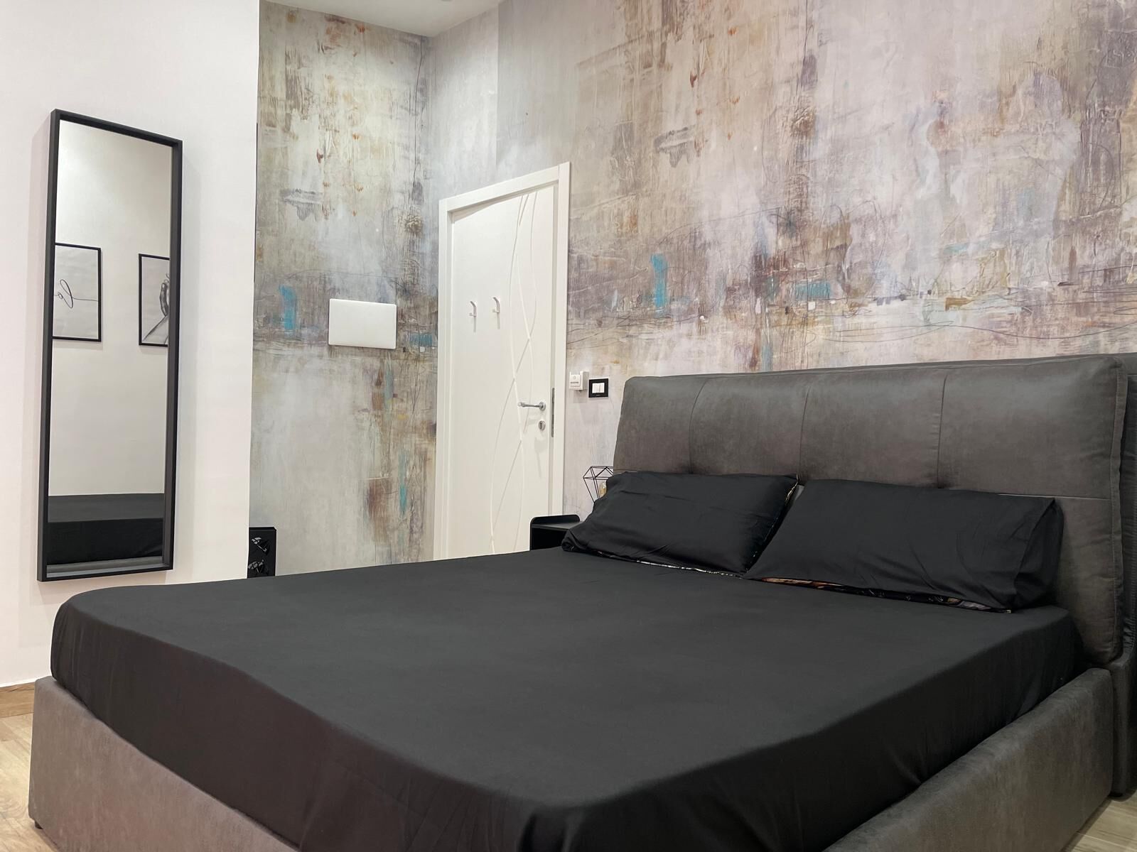 Un dormitorio moderno con una cama grande, un armario y un espejo montado en la pared.
