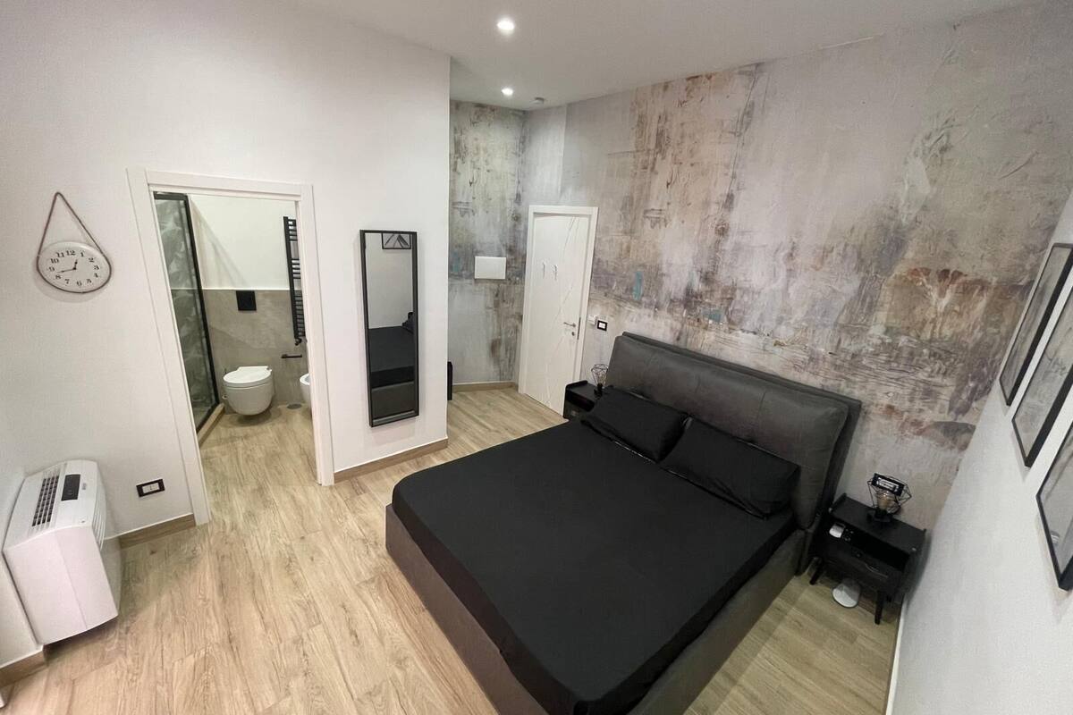 Une chambre moderne dotée d’un grand lit, d’un dressing et d’une salle de bain avec des toilettes et un lavabo.