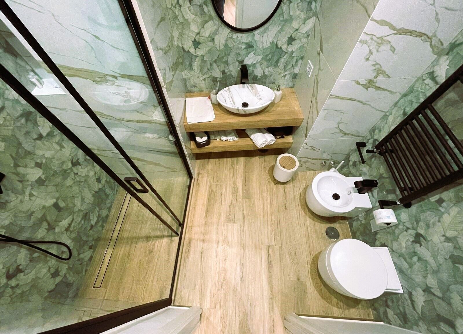 Une salle de bain avec un meuble-lavabo en bois, deux vasques, des toilettes et un espace douche.