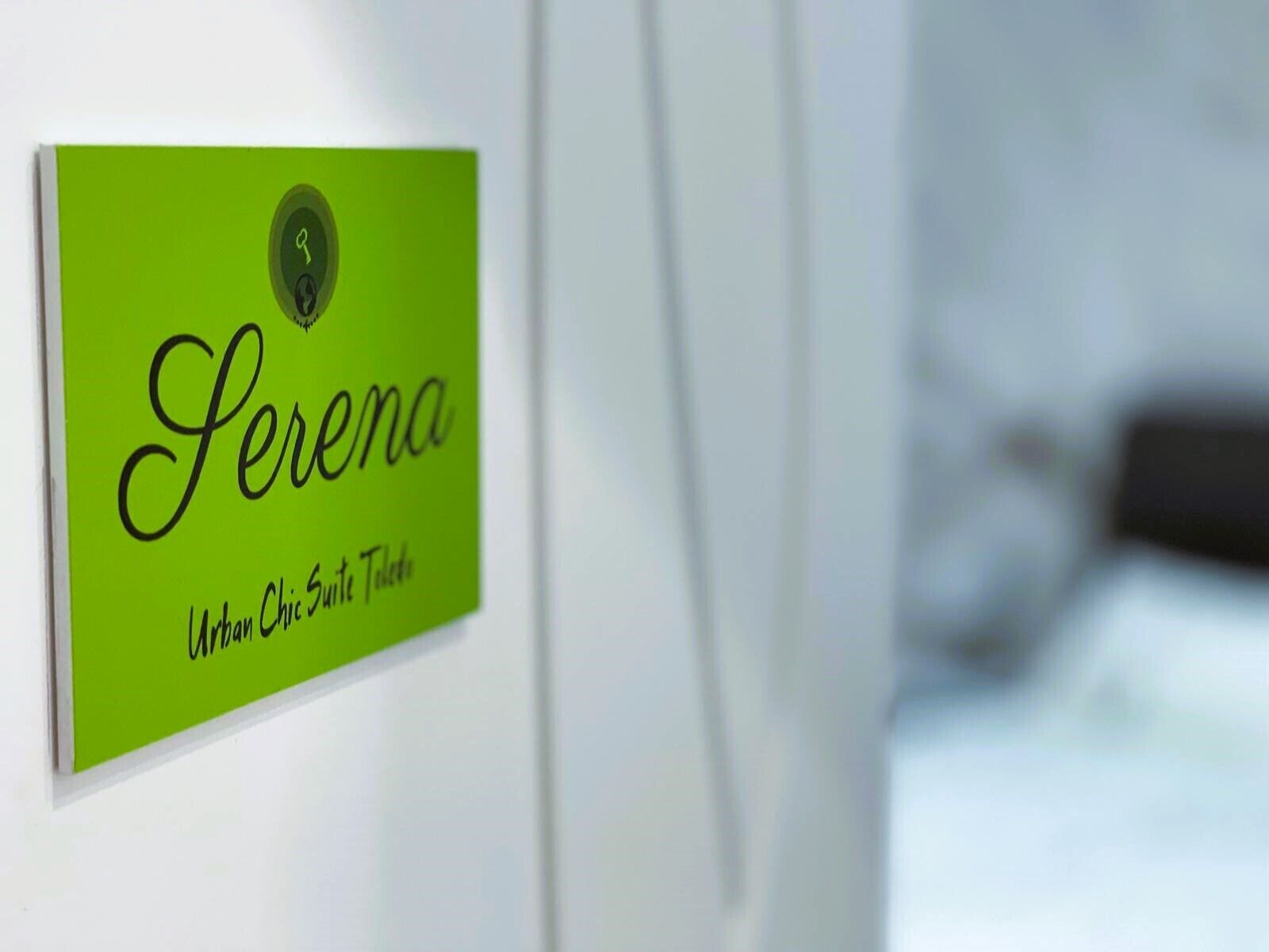 Un panneau vert portant le nom « Serena » et l’inscription « Urban Chic Suite Hotel », le tout sur un mur blanc.