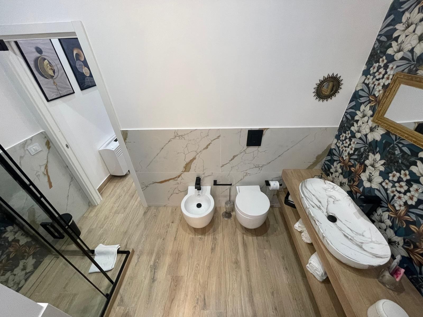 Ein modernes Badezimmer mit zwei Toiletten, einem Waschbecken und einer Dusche.