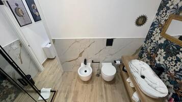 Ein modernes Badezimmer mit zwei Toiletten, einem Waschbecken und einer Dusche.