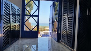 A view through a metal gate leading to a balcony with a tiled floor and a bed. - Nice house with sea view douar Oualed Hlal, 8km from Oualidia (Oualidia)
