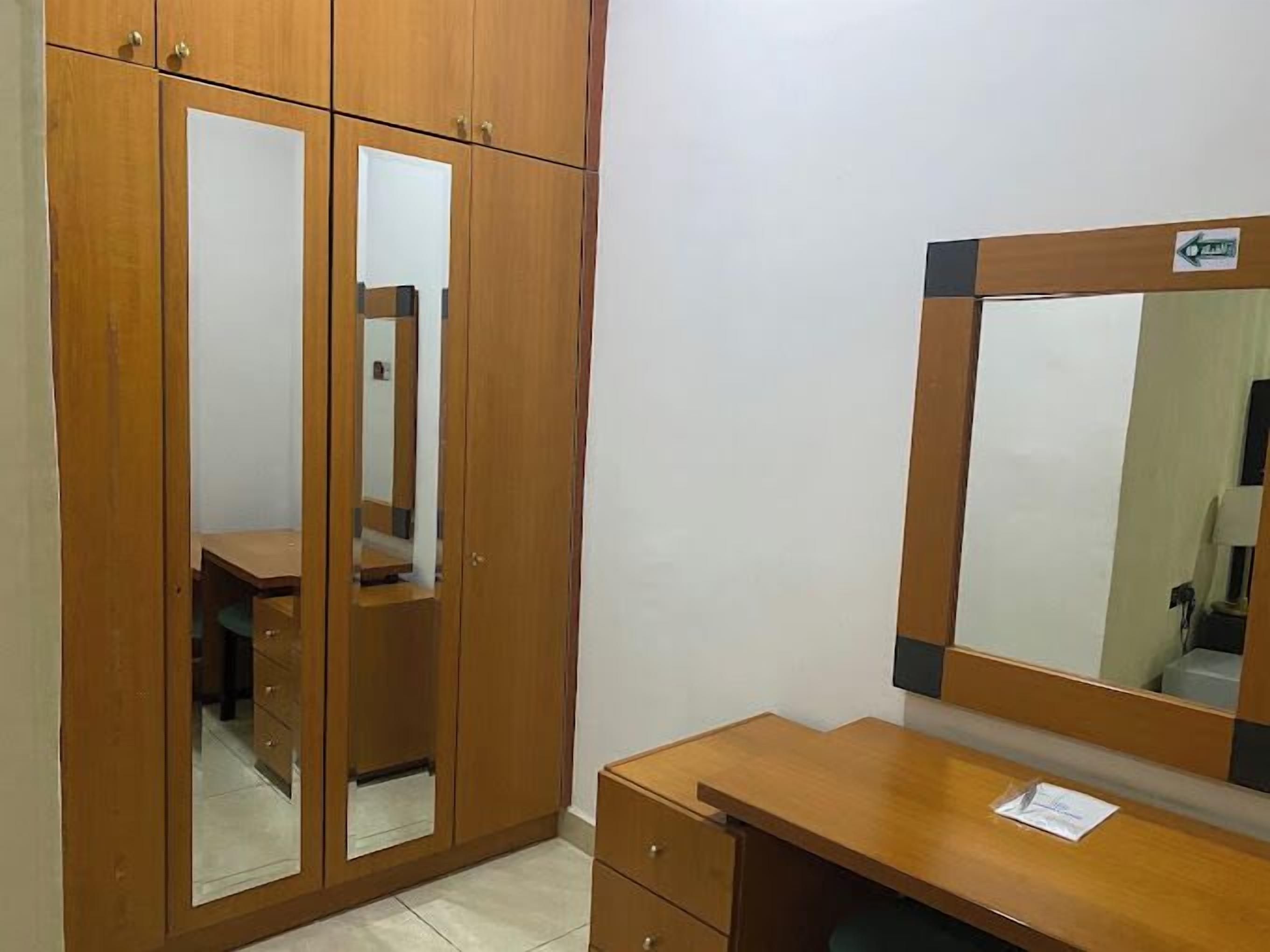 Una habitación con un armario de madera, un espejo y un escritorio.