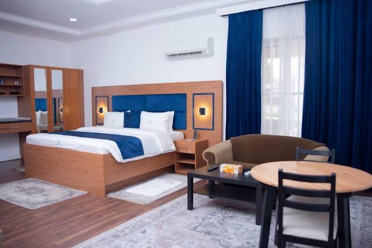 A hotel room with a bed, a desk, a chair, and a small table.