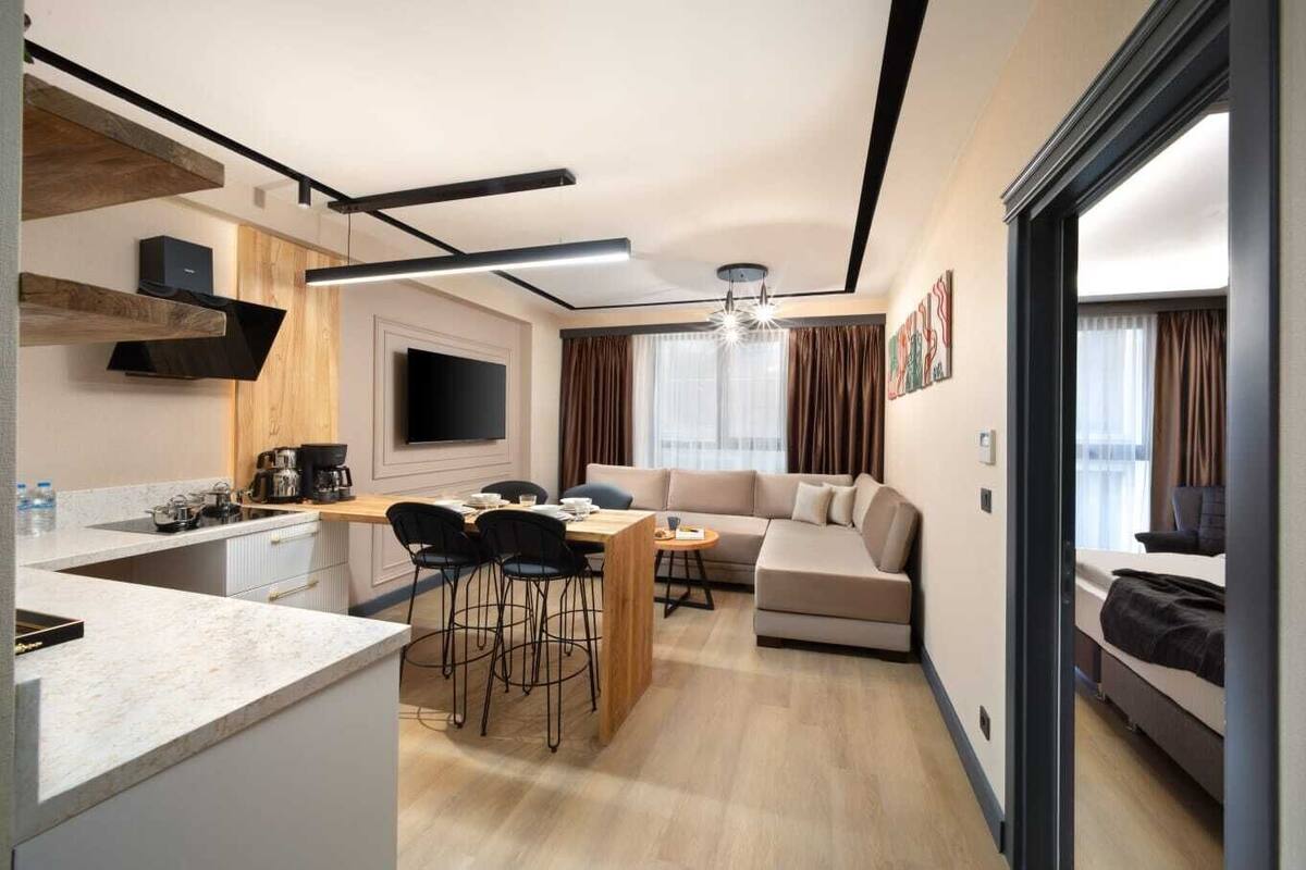 A modern hotel room with a kitchen, dining area, and a living space.