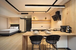 A modern kitchen with a wooden island, black chairs, and a coffee maker. - Şişli Family Time Suites (Istanbul)