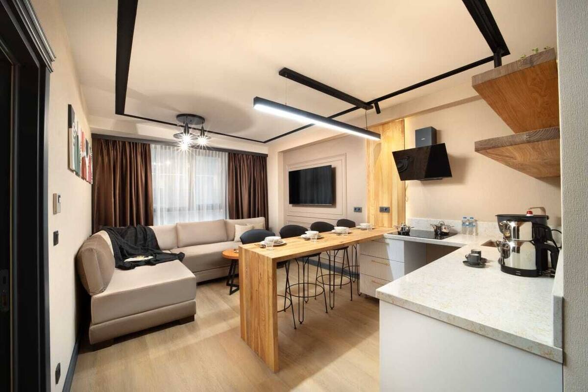 A compact hotel room with a sofa, a dining table, and a kitchenette.