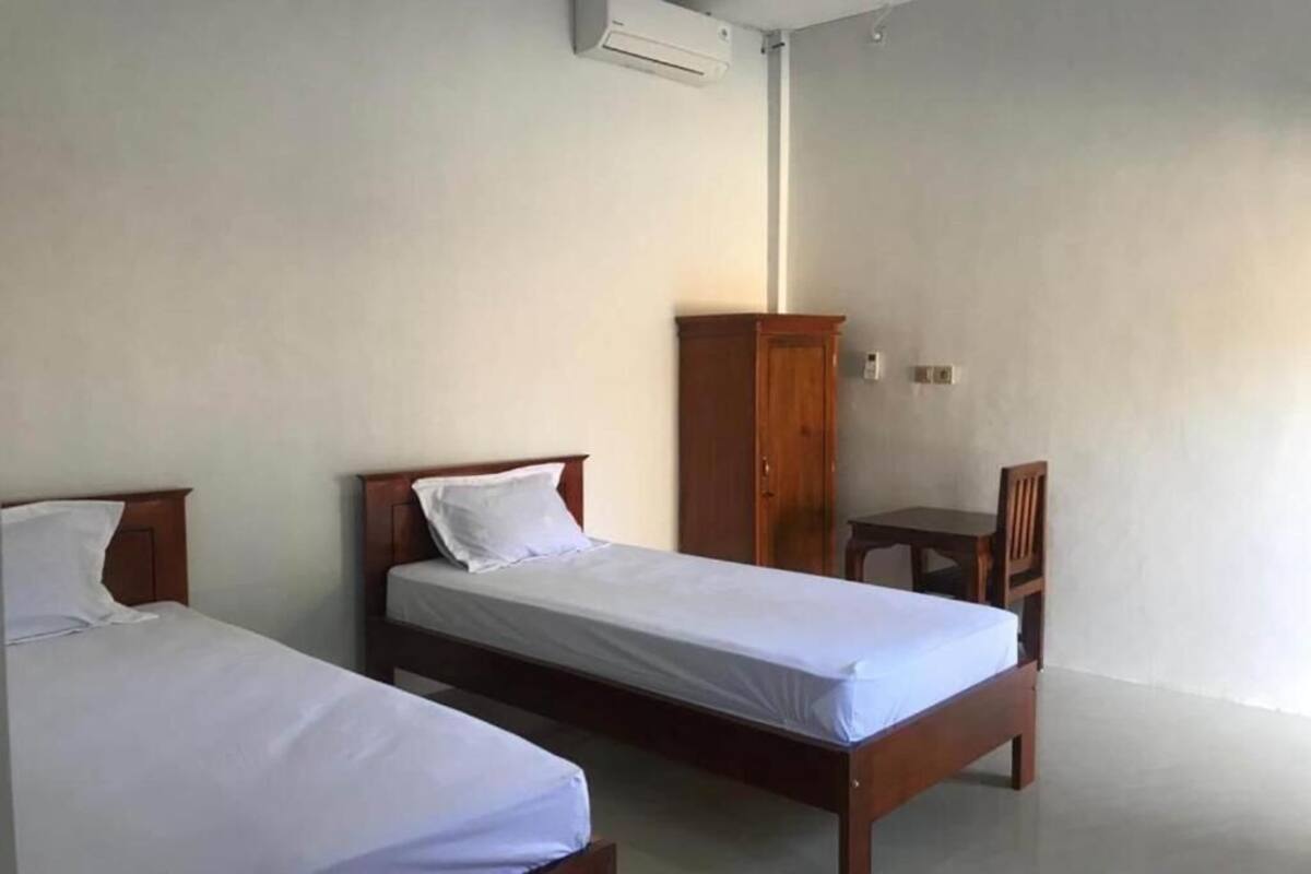 A room with two single beds, a wooden wardrobe, and a small table.