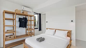 A modern bedroom with a wooden bed frame, white bedding, a wooden wardrobe with baskets, and a bench.