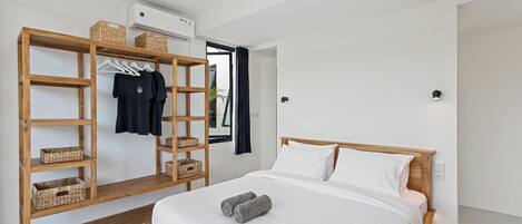 Une chambre à coucher moderne avec un cadre de lit en bois, du linge de lit blanc, une armoire en bois dotée de paniers et un banc.