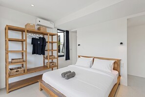 A modern bedroom with a wooden bed frame, white bedding, a wooden wardrobe with baskets, and a bench. - White Residence - Art & Boutique Suites (Keroboken Kelod)