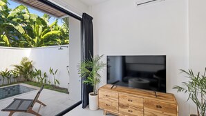 Una sala de estar moderna con un televisor de pantalla plana, un mueble de madera y una planta en maceta.
