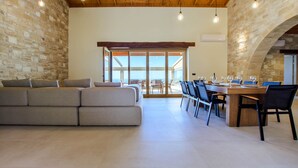 Amplia sala de estar con un sofá grande, una mesa de comedor con sillas y vistas a una terraza exterior a través de una puerta de cristal.