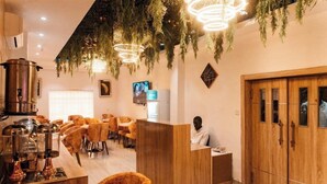 Una hall d'albergo con reception, armadietti in legno e un'area salotto con sedie.