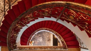 Una maestosa scalinata con gradini rossi e ringhiere dorate finemente decorate.