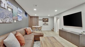 A modern living room with a sofa, coffee table, and a flat-screen TV mounted on the wall.