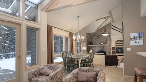 Una sala de estar acogedora con chimenea, comedor y ventanas amplias.