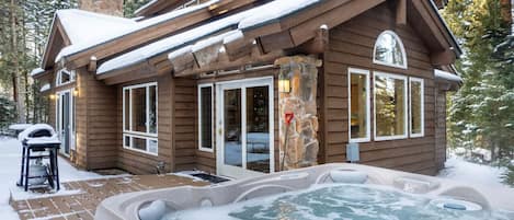 Une cabane en rondins avec un jacuzzi et une cheminée en pierre.