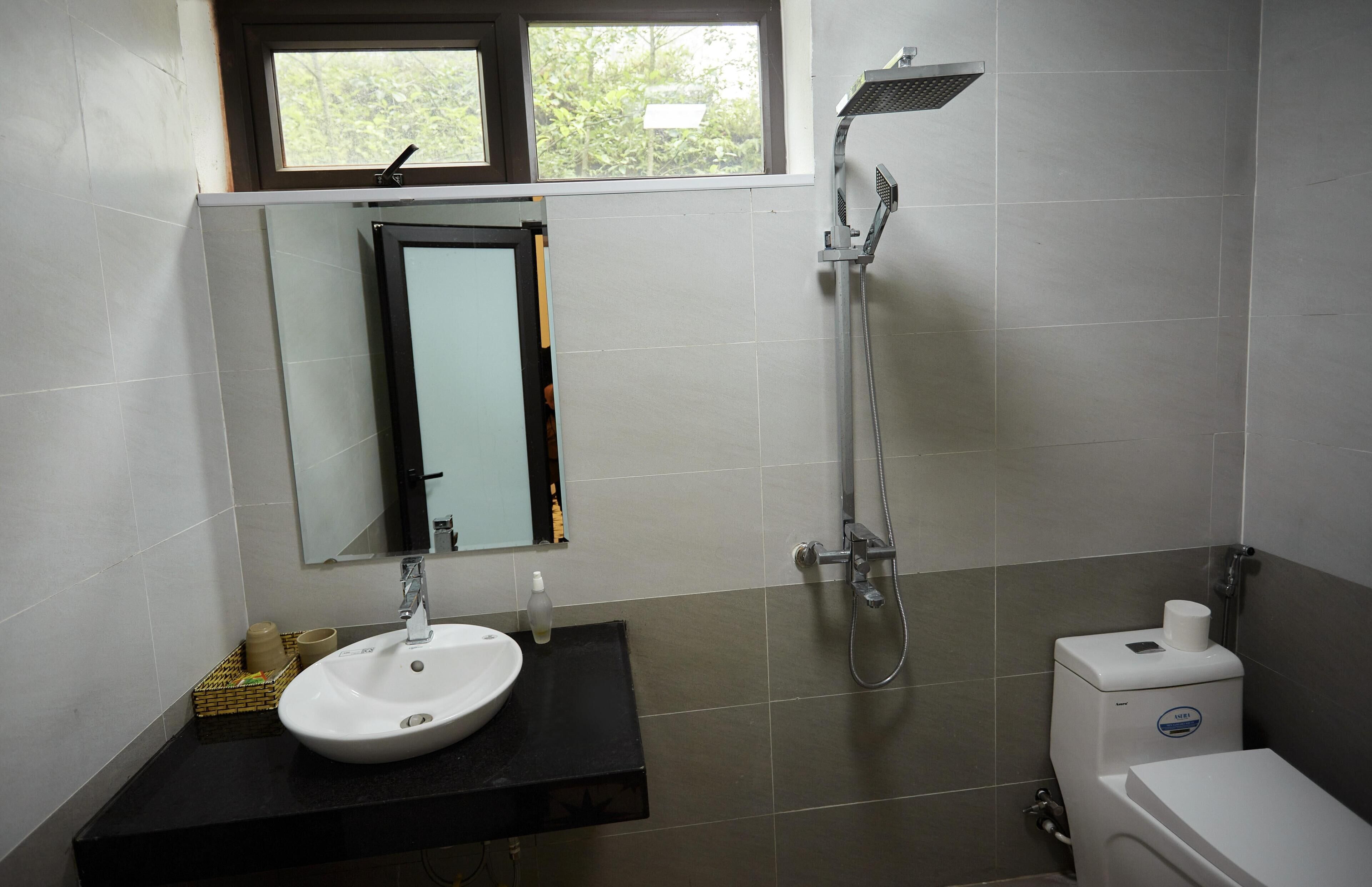 A bathroom with a sink, mirror, shower, and toilet.