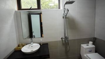 A bathroom with a sink, mirror, shower, and toilet.
