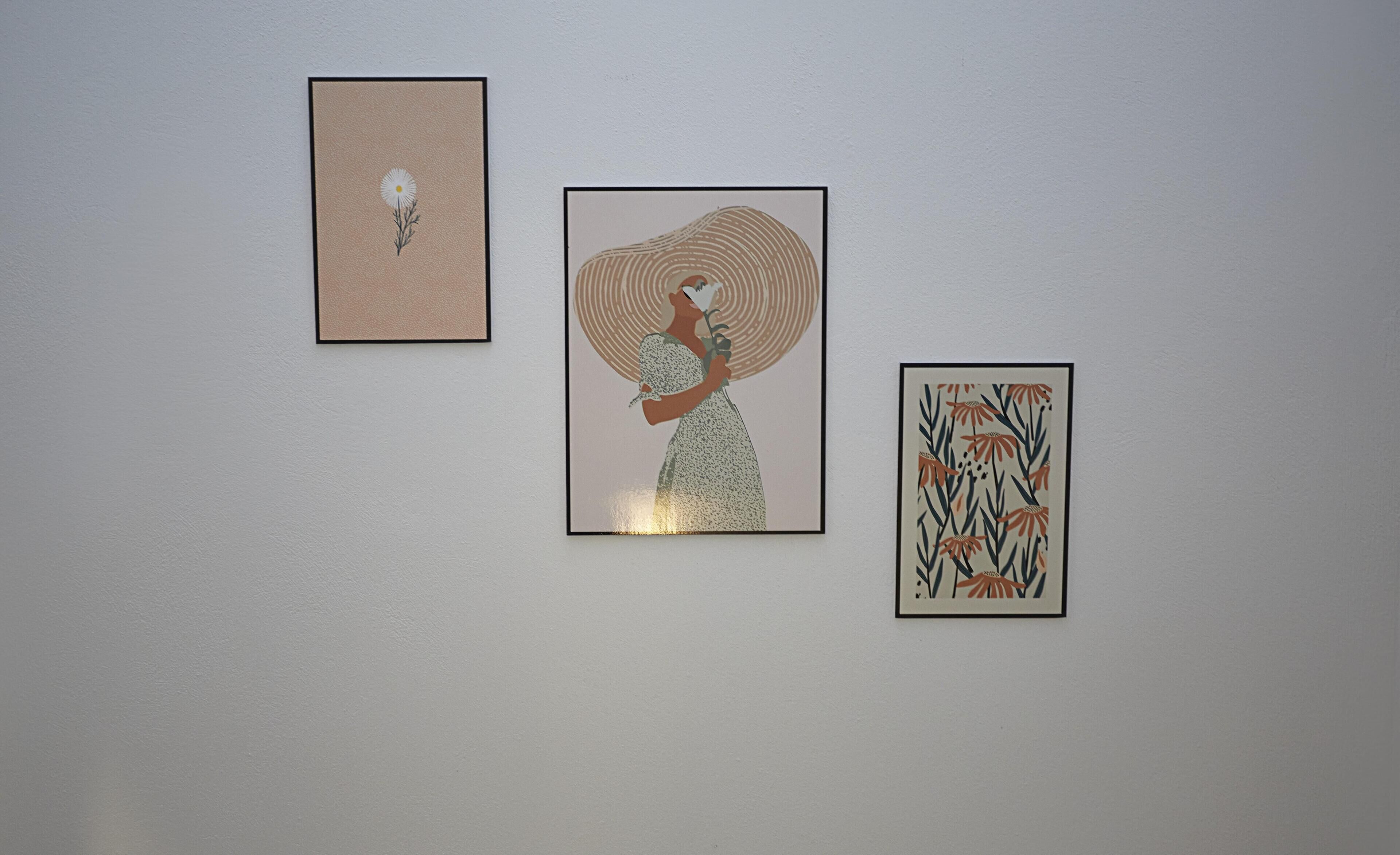 Three framed artworks on a plain wall.