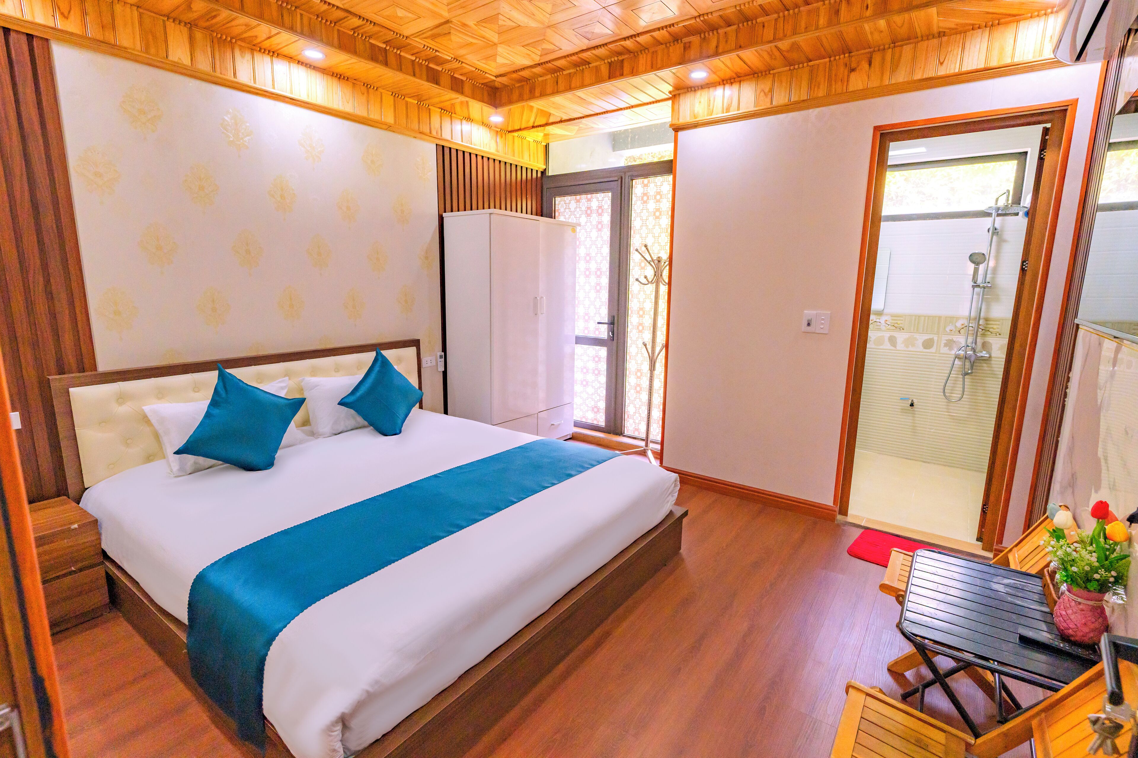 A bedroom with a bed, a wardrobe, a table with chairs, and a shower area.