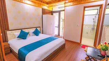 A bedroom with a bed, a wardrobe, a table with chairs, and a shower area.