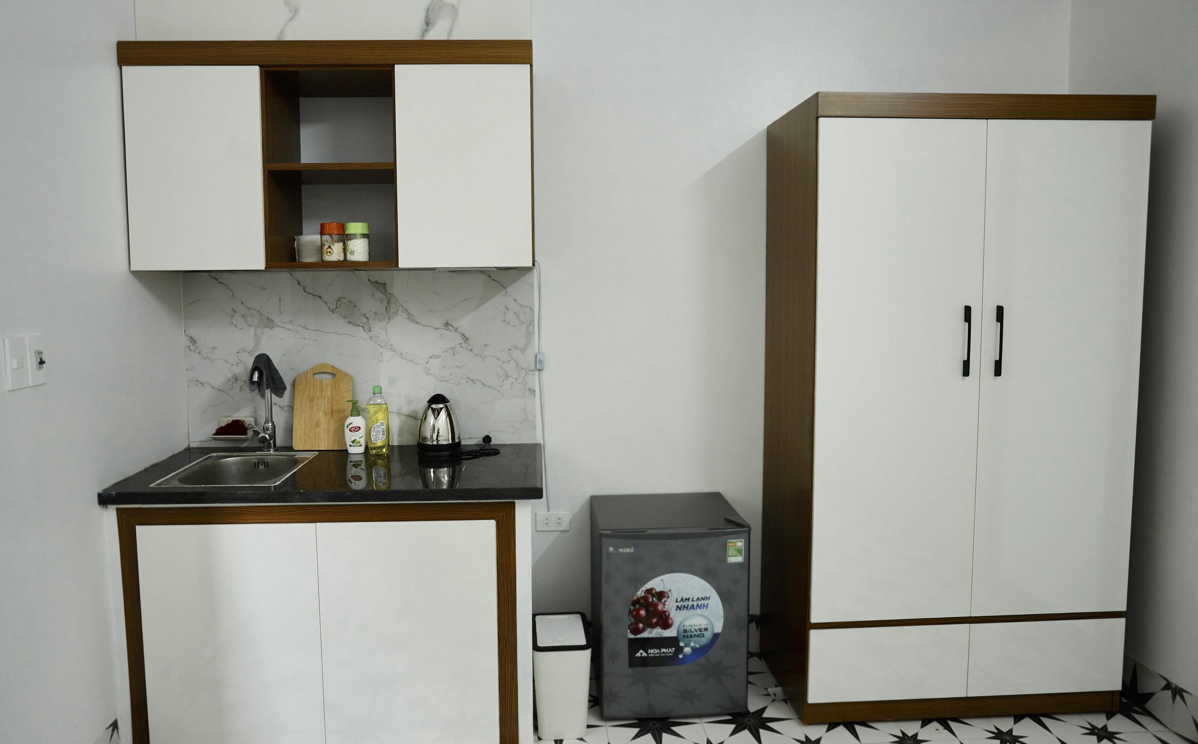 Una cocina compacta con salpicadero de mármol, encimera de madera y un refrigerador.