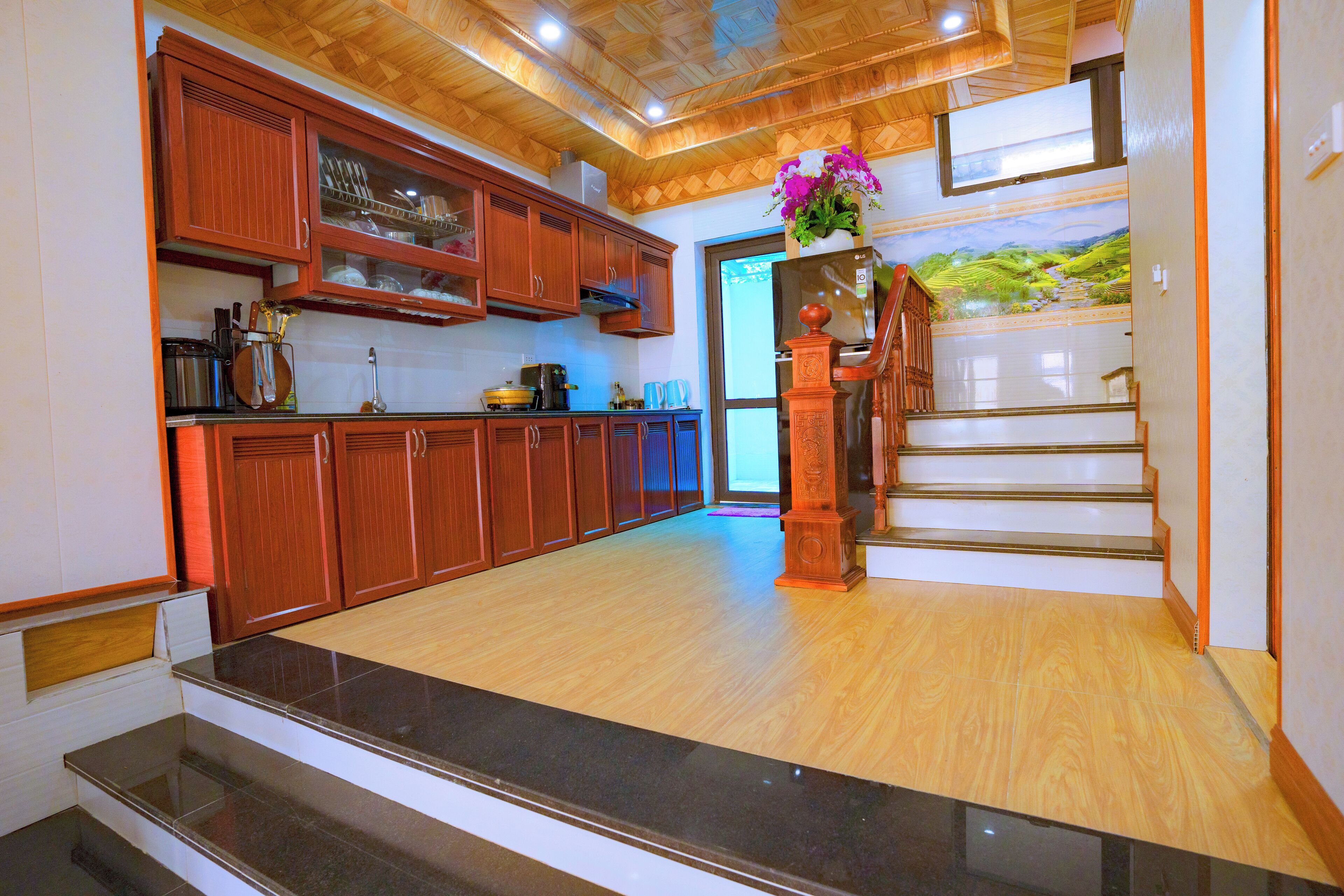 A spacious kitchen with wooden cabinets, a granite countertop, and a staircase leading to an upper level.