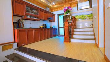 A spacious kitchen with wooden cabinets, a granite countertop, and a staircase leading to an upper level.