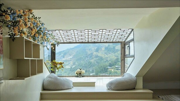 Un intérieur moderne offrant une vue sur un paysage montagneux grâce à une grande fenêtre, un plafond au design géométrique et un escalier aux lignes épurées.