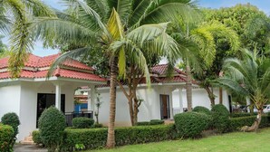 A white building with a red-tiled roof, surrounded by well-maintained hedges and palm trees. - El Matcha Lanta Resort (Ko Lanta)