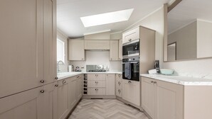 Eine moderne Küche mit hellen Holzschränken, einem Fischgrätparkett, einem Oberlicht und Edelstahlgeräten.