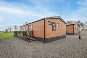 Une maison mobile en bois, de plain-pied, avec un petit porche et un escalier menant à l’entrée.