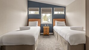 Ein Doppelzimmer mit zwei Betten, einem kleinen Nachttisch aus Holz und einem Fenster mit Jalousien.