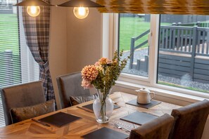 A dining table with a vase of flowers, a teapot, and a laptop. - Lodge No 85 | Hot Tub | Stewart's Resort Cameron (Cameron)
