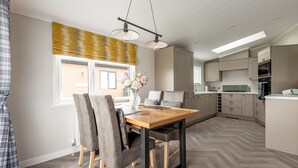 Eine moderne Küche mit einer zentralen Kochinsel, eingebauten Geräten und einem Essbereich mit einem Holztisch und Stühlen.