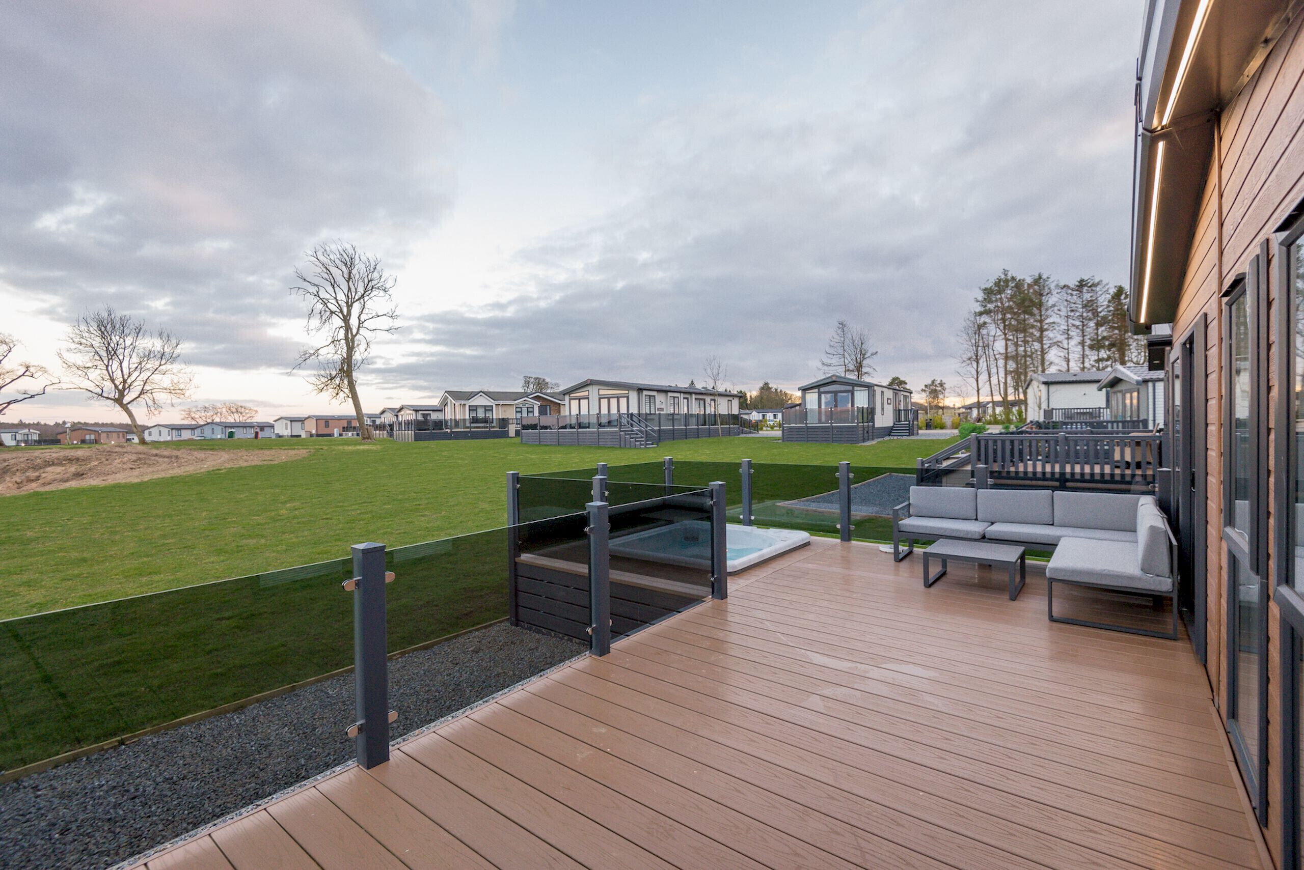 Una terraza con asientos exteriores y una vista de casas móviles al fondo.