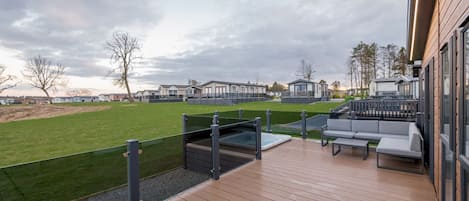 Una terraza con asientos exteriores y una vista de casas móviles al fondo.
