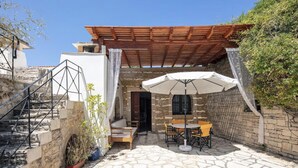 A stone patio with a wooden pergola, outdoor seating, and a staircase leading to an upper level. - Villa Anta With 2 Bedrooms and 1 Bathrooms (Rethymno)