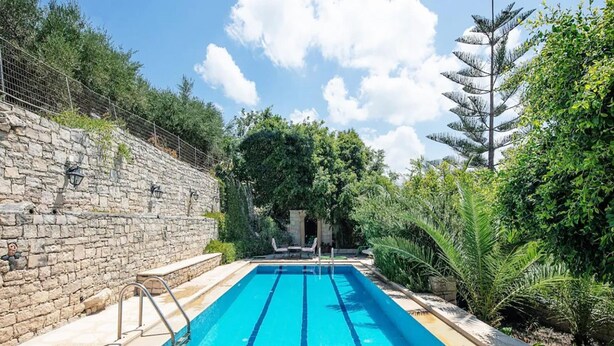 A rectangular swimming pool with clear blue water, surrounded by stone walls and lush greenery. - Villa Anta With 2 Bedrooms and 1 Bathrooms (Rethymno)