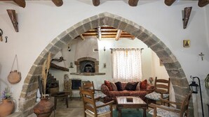 A cozy living room with a stone archway, rustic furniture, and a fireplace. - Villa Anta With 2 Bedrooms and 1 Bathrooms (Rethymno)