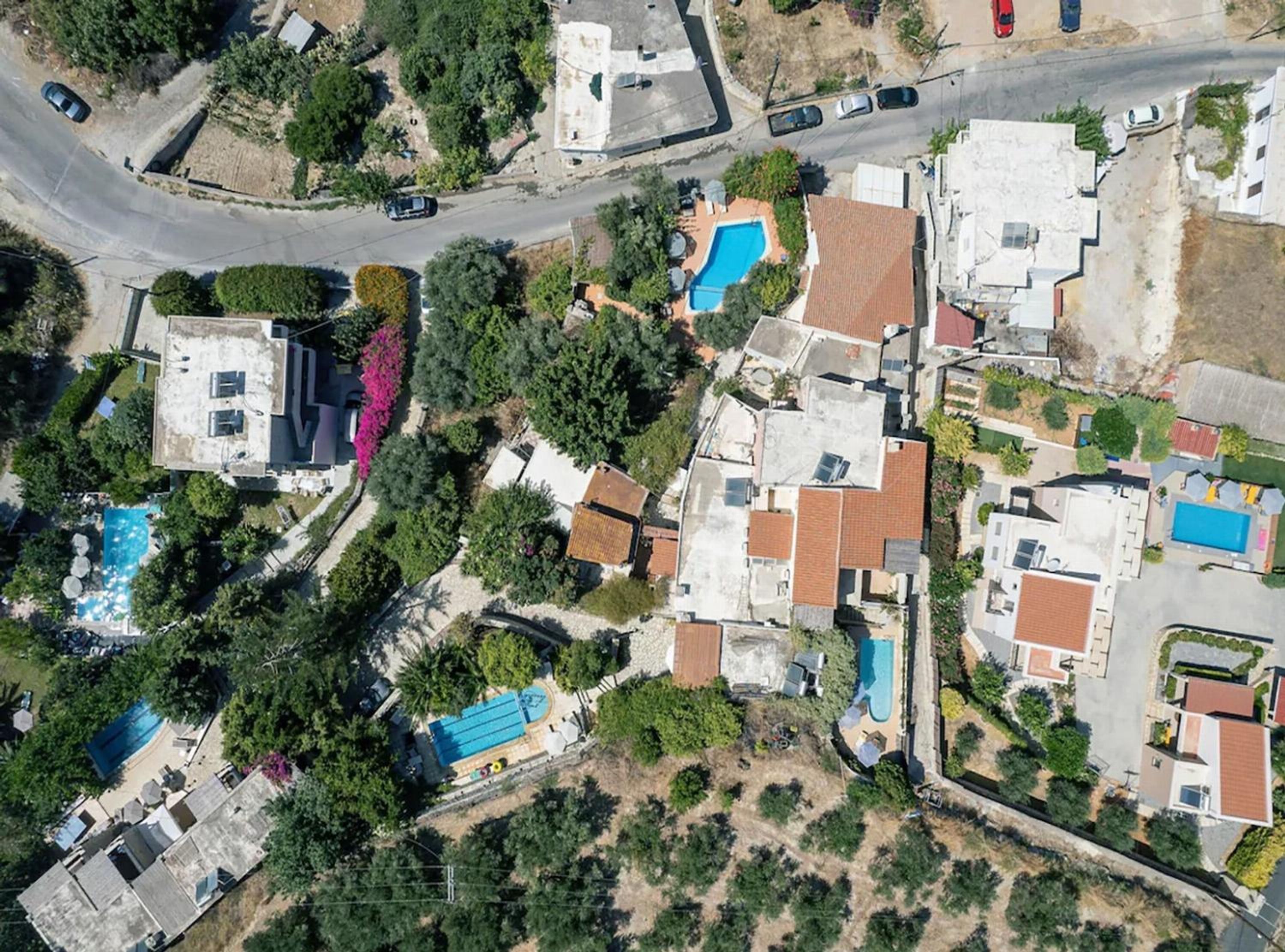 An aerial view of a residential area with multiple houses, roads, and a swimming pool.