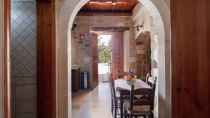 A narrow hallway with a wooden door leading to a dining area with a table set for two. - Villa Anta With 2 Bedrooms and 1 Bathrooms (Rethymno)