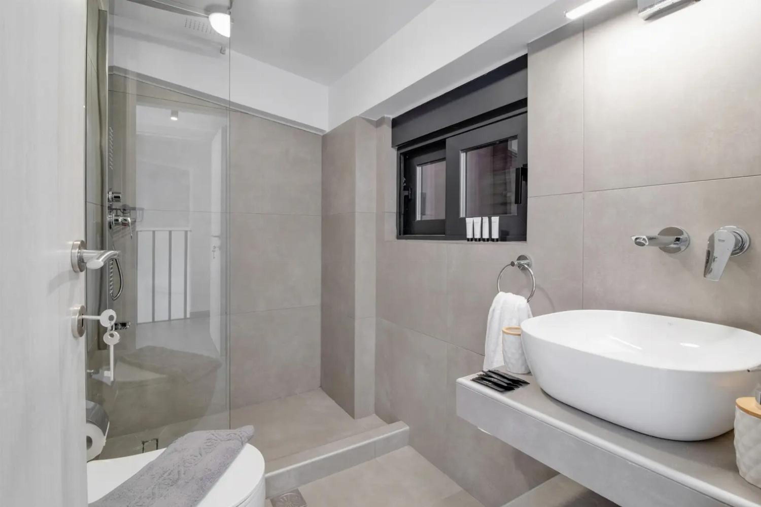 A modern bathroom with a glass-enclosed shower, a white sink, and a towel rack.