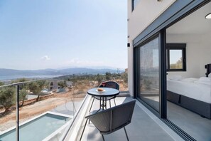 Un balcon moderne doté d’une rambarde en verre, offrant une vue panoramique sur un paysage magnifique.