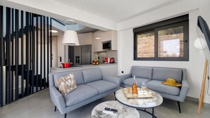 A modern living room with two grey sofas, a marble coffee table, and a kitchen in the background. - Villa Andria With 5 Bedrooms and 5 Bathrooms (Lefkada)